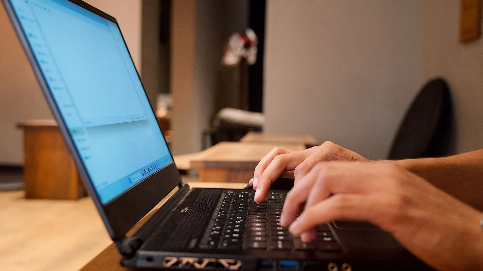 Hands typing on a laptop at an office desk