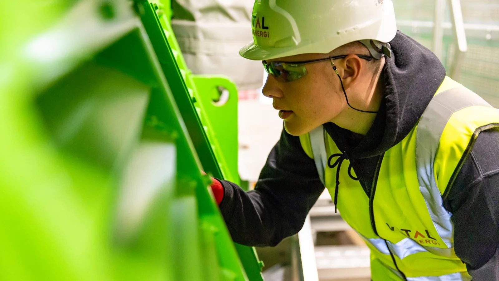 A worker wearing a safety helmet beside industrial equipment