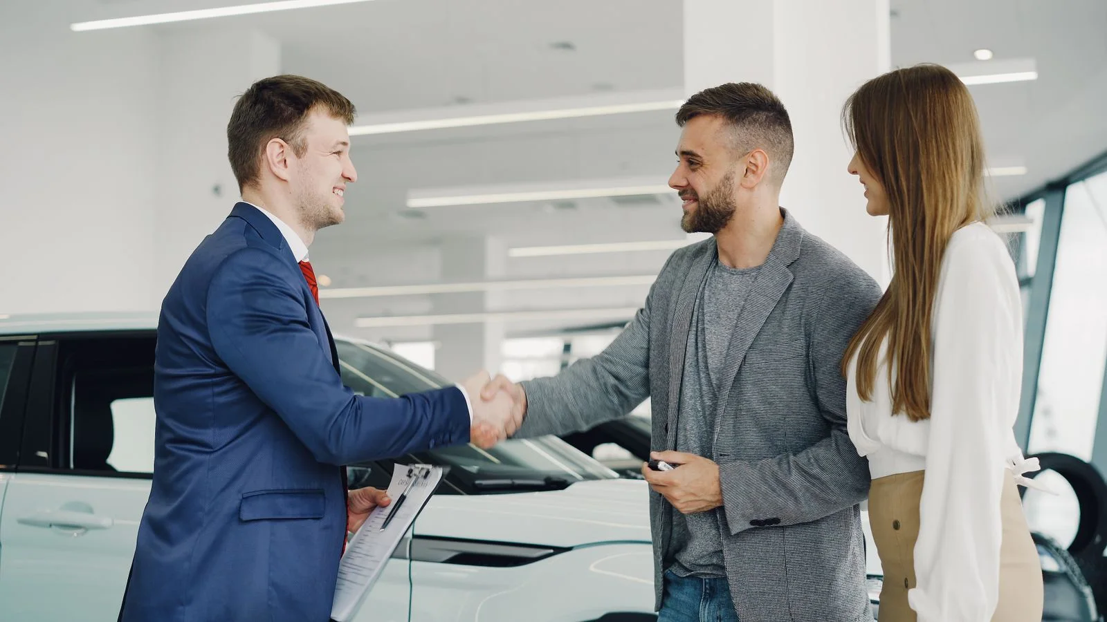 A car salesperson shaking hands with customers in a showroom