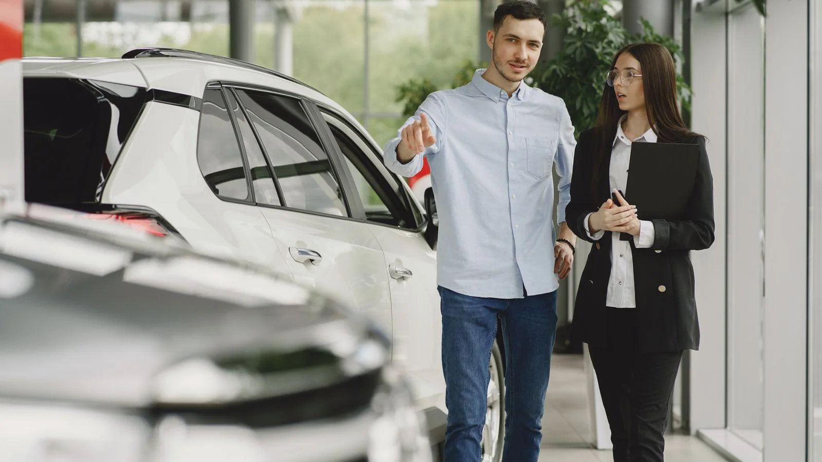 A salesperson and customer discussing a car in a showroom