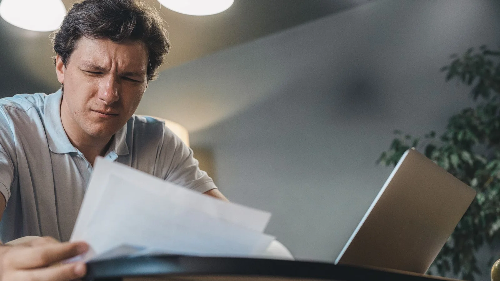 A professional reviewing documents beside a laptop